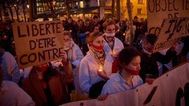 Manifestantes con paños cubriéndose la boca sostienen un lema que dice "Libertad para estar en contra" durante una manifestación silenciosa provida en París, cuando el Senado inició debates para la inclusión del aborto en la constitución.
