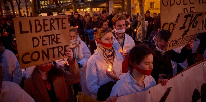 Manifestantes con paños cubriéndose la boca sostienen un lema que dice "Libertad para estar en contra" durante una manifestación silenciosa provida en París, cuando el Senado inició debates para la inclusión del aborto en la constitución.