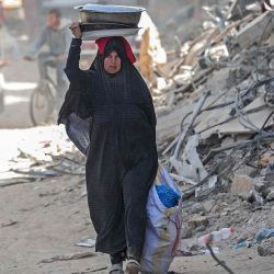 Una mujer palestina desplazada carga sus pertenencias por una calle entre los escombros de casas destruidas por el bombardeo israelí en Khan Yunis. Foto de AFP | Foto:AFP