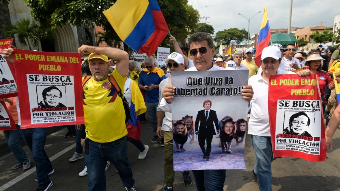 A demonstrator holds a placard depicting Argentine President Javier Milei, El Salvador's President Nayib Bukele, US ex-president Donald Trump, Colombia's opposition leader, senator María Fernanda Cabal, and Ecuador's President Daniel Noboa during a march against the government of Colombian President Gustavo Petro over health and pension reforms in Cali, Colombia, on March 6, 2024.