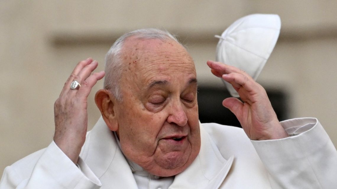 Wind blows Pope Francis' cap off his head as he arrives for his general audience in St Peter Square at the Vatican on March 13, 2024. 