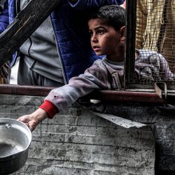 Un niño sostiene una olla vacía mientras espera con otros palestinos desplazados que hacen cola para recibir comidas proporcionadas por una organización benéfica antes de la comida "iftar" para romper el ayuno durante el mes sagrado musulmán del Ramadán, en Rafah, en el sur de la Franja de Gaza, en medio del conflicto en curso en el territorio palestino entre Israel y el grupo militante Hamás. | Foto:SAID KHATIB / AFP