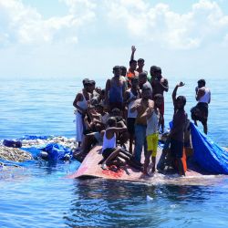 Refugiados rohingya esperan ser rescatados del casco de su barco volcado mientras un barco de la Agencia Nacional de Búsqueda y Rescate (BASARNAS) se acerca a unas 16 millas náuticas (29 kilómetros) al oeste de Aceh, Indonesia. | Foto:Zahlul Akbar / AFP