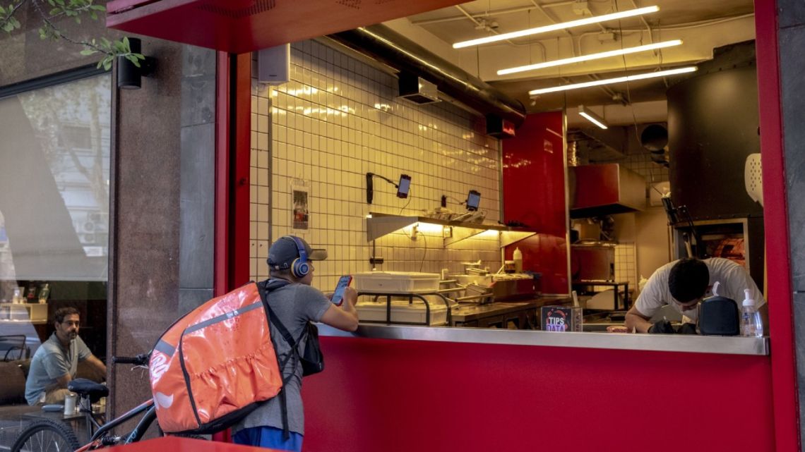 A delivery worker waits for an order outside a restaurant in Buenos Aires.