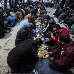 La gente se sienta junta para romper el ayuno durante el mes sagrado del Ramadán en una comida masiva "iftar" organizada por miembros del campo de refugiados de Barbara, a lo largo de una calle de Rafah, en el sur de la Franja de Gaza, en medio de el actual conflicto entre Israel y el grupo militante Hamás. | Foto:MOHAMMED ABED / AFP