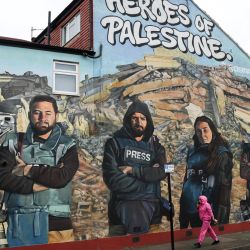 Un peatón pasa junto a un mural realizado por los artistas callejeros Auberi Chen, Core 246 y el Capitán Kris que representa a los fotógrafos palestinos Mohammed Al-Masri, Ali Jadallah, Abdelhakim Abu Riash y el periodista palestino Hind Khoudary en Ilford, al este de Londres, como parte de un proyecto lanzado por la plataforma de arte Creative Debuts llamado "Heroes of Palestina".  | Foto:DANIEL LEAL / AFP