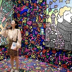 Un visitante toma fotografías de las obras del artista británico Mr Doodle en Art Basel en Hong Kong. | Foto:PETER PARKS / AFP