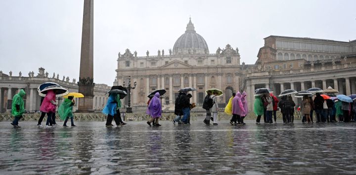 Los turistas caminan bajo una fuerte lluvia después de la audiencia general semanal en la plaza de San Pedro en el Vaticano.