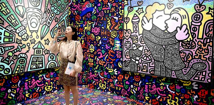 Un visitante toma fotografías de las obras del artista británico Mr Doodle en Art Basel en Hong Kong.