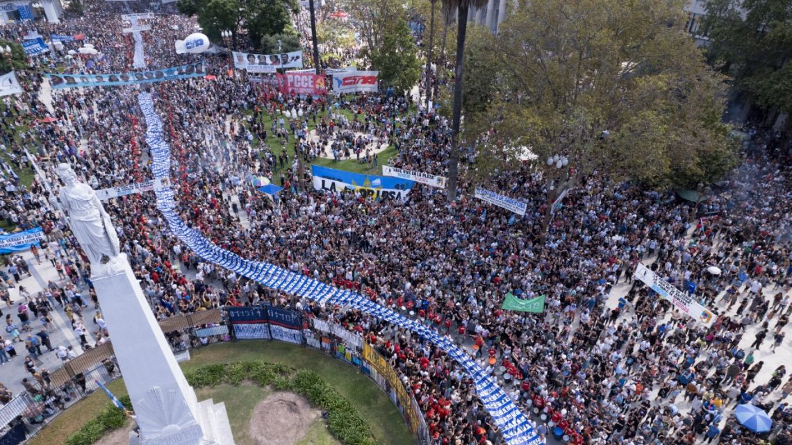 In this aerial view hundreds hold a large banner with portraits of people who disappeared during the military dictatorship (1976-1983) upon arrival at Plaza de Mayo Square to commemorate the 48th anniversary of the coup.