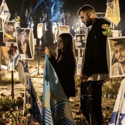 Familiares de las víctimas de los ataques del 7 de octubre llevados a cabo por militantes palestinos visitan una instalación con fotografías de sus seres queridos que fueron asesinados o secuestrados durante el evento, en el lugar del festival Nova en Re'im, en el sur de Israel. | Foto:MENAHEM KAHANA / AFP