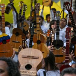 Estudiantes levantan su cuatro durante el día nacional del instrumento musical en la Plaza Bolívar de Caracas. El cuatro es un instrumento de cuatro cuerdas de origen colonial de la familia de las guitarras que se utiliza en todos los ritmos folclóricos de Venezuela y Colombia. | Foto:JUAN BARRETO/AFP