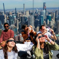 La gente mira hacia el cielo en la plataforma de observación 'Edge at Hudson Yards' antes de un eclipse solar total en América del Norte, en la ciudad de Nueva York. | Foto:CHARLY TRIBALLEAU / AFP