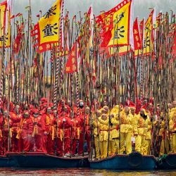 Los participantes sostienen postes y banderas en sus barcos tradicionales durante el Festival de Barcos Jiangyan Qintong de Taizhou en el Parque Nacional de Humedales Qinhu en Taizhou, en el este de China. | Foto:AFP