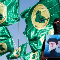 Un miembro de los Batallones Imam Ali, el brazo armado del Movimiento Islámico de Irak, una facción miembro de los paramilitares de las Fuerzas de Movilización Popular (PMF), sostiene una fotografía que representa a los actuales y fallecidos líderes supremos de Irán, el ayatolá Ruhollah Jomeini y Ali Khamenei, mientras otros miembros del grupo se reúnen con sus banderas durante una manifestación para conmemorar las conmemoraciones anuales del día de Quds (Jerusalén) en Bagdad. | Foto:MURTAJA LATEEF / AFP