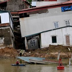 Una mujer en un barco observa casas dañadas a orillas del río Cau en la provincia de Bac Ninh, Vietnam. Media docena de casas residenciales junto al río se derrumbaron en el río Cau debido a la erosión de la tierra según las autoridades locales. | Foto:NHAC NGUYEN / AFP