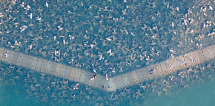 Esta fotografía aérea muestra a personas caminando sobre un rompeolas en la ciudad de Chongqing, en el suroeste de China.