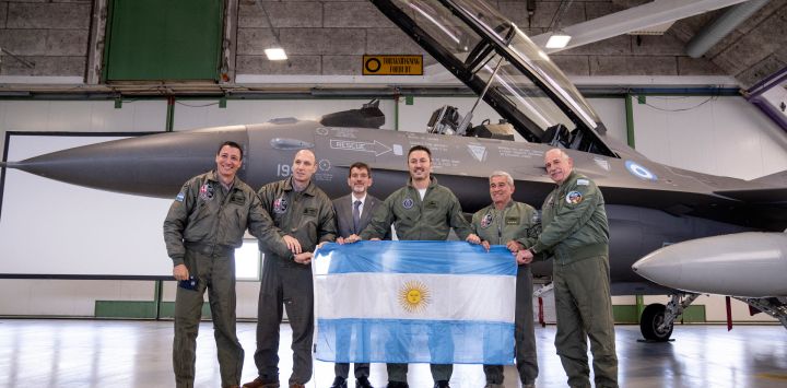 Los miembros de la delegación argentina, incluido el ministro de Defensa, Luis Alfonso Petri, sostienen su bandera nacional mientras posan frente a un caza F-16 durante un evento de prensa al margen de la firma de un acuerdo sobre la compra de aviones F-16 daneses. en la Base Aérea de Skrydstrup, Dinamarca. Argentina firmó un contrato para comprar 24 aviones de combate daneses F-16.
