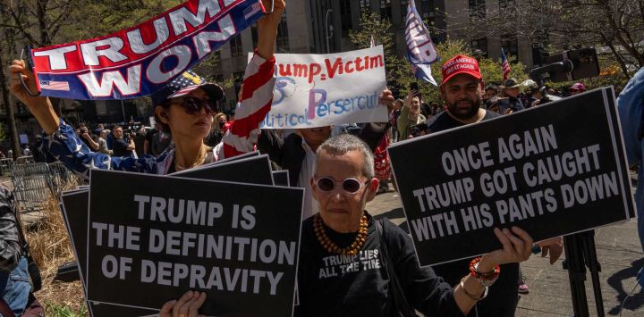 Manifestantes pro-Trump y anti-Trump sostienen carteles frente al Tribunal Penal de Manhattan mientras el expresidente estadounidense Donald Trump asiste al primer día de su juicio por supuestamente encubrir pagos de silencio relacionados con relaciones extramatrimoniales, en la ciudad de Nueva York.