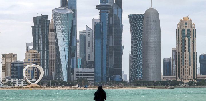 Una mujer junto al mar en la cornisa de Doha, frente a los rascacielos en el distrito de West Bay.