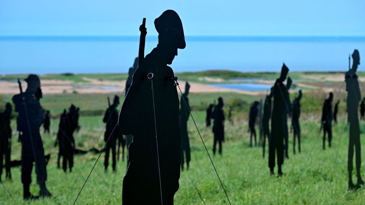 Esta fotografía muestra siluetas de madera de soldados británicos instaladas como parte de la instalación "De pie con gigantes" en el Memorial Británico de Normandía de la Segunda Guerra Mundial. | Foto:Damien Meyer / AFP