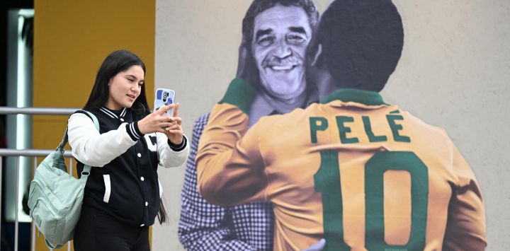 Una mujer se toma una selfie frente a una pancarta con imágenes del fallecido premio Nobel colombiano Gabriel García Márquez y la leyenda del fútbol brasileño Pelé en la Feria Internacional del Libro de Bogotá, que tiene a Brasil como invitado de honor, en Bogotá.