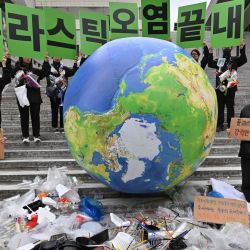 Activistas medioambientales sostienen carteles que dicen "¡Acabemos con la contaminación plástica!". mientras exhiben desechos plásticos con un globo terrestre durante un evento de campaña para conmemorar el Día Internacional de la Tierra en Seúl. | Foto:Jung Yeon-je / AFP