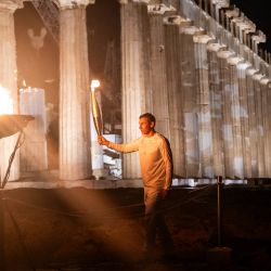 El campeón griego de 400 metros, Periklis Iakovakis, sostiene la llama olímpica frente al antiguo templo del Partenón en la cima de la colina de la Acrópolis durante el relevo de la antorcha olímpica en Atenas. | Foto:Angelos Tzortzinis / AFP