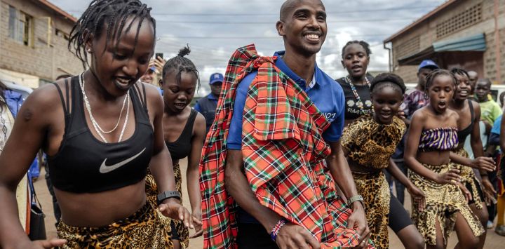 El corredor retirado somalí-británico Mo Farah baila con jóvenes bailarines kenianos durante su llegada para participar en el torneo anual de la Copa de Fútbol Mo Farah para inmigrantes urbanos en la Asociación de Deportes Juveniles Mathare en Nairobi, Kenia.