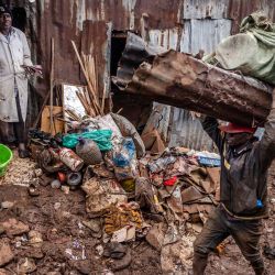 Un hombre recoge algunas de sus pertenencias mientras otros cargan varios materiales después de que sus casas fueran destruidas por las inundaciones tras las lluvias torrenciales en el asentamiento informal Mathare en Nairobi, Kenia. | Foto:LUIS TATO/AFP