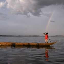 Una vista general de un arco iris mientras un joven se mueve en su piragua por el río Congo, República Democrática del Congo. | Foto:Arsène Mpiana / AFP