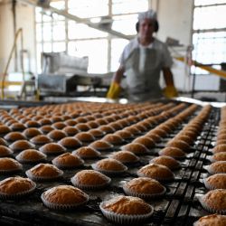 Un trabajador inspecciona los pastelitos que salen del horno en la fábrica de Dulcypas en La Matanza, provincia de Buenos Aires. | Foto:LUIS ROBAYO / AFP
