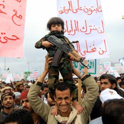Un niño parado sobre los hombros de un hombre sostiene un rifle durante una manifestación pro-palestina y anti-israelí en Saná, la capital controlada por los hutíes, en medio del conflicto en curso en la Franja de Gaza entre Israel y el grupo militante palestino Hamás. | Foto:MOHAMMED HUWAIS / AFP