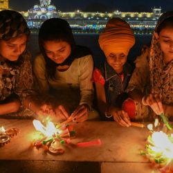 Devotos sij encienden velas en el Templo Dorado iluminado con motivo del aniversario del nacimiento de Guru Tegh Bahadur, en Amritsar, India. | Foto:Narinder Nanu / AFP
