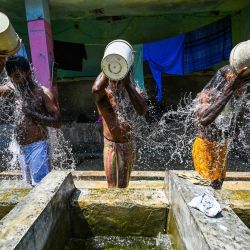 Hombres se bañan en un pozo público en un caluroso día de verano en Colombo, Sri Lanka. | Foto:ISHARA S. KODIKARA / AFP