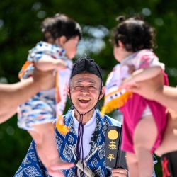 Los luchadores de sumo sostienen a los niños durante su partido de "sumo del bebé que llora" en el templo Sensoji en Tokio. Los padres japoneses creen que los luchadores de sumo pueden ayudar a que los bebés lloren y deseen crecer con buena salud. | Foto:Philip Fong / AFP