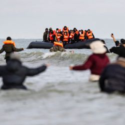 Los migrantes saludan al barco de un contrabandista en un intento de cruzar el Canal de la Mancha, en la playa de Gravelines, cerca de Dunkerque, al norte de Francia. Cinco migrantes, incluida una niña de siete años, murieron tratando de cruzar el Canal de la Mancha desde Francia a Gran Bretaña, dijeron las autoridades locales, pocas horas después de que Gran Bretaña aprobara un controvertido proyecto de ley para deportar a los solicitantes de asilo a Ruanda. | Foto:SAMEER Al-DOUMY / AFP