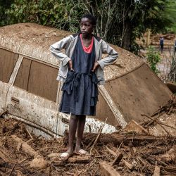 Una niña observa junto a un coche averiado enterrado en barro en una zona muy afectada por lluvias torrenciales e inundaciones repentinas en la aldea de Kamuchiri, cerca de Mai Mahiu, Kenia. | Foto:LUIS TATO/AFP