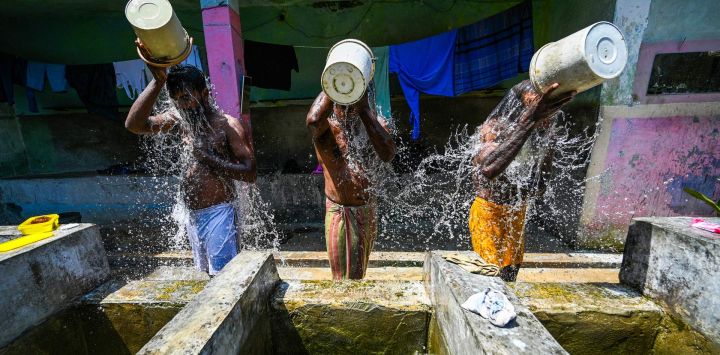 Hombres se bañan en un pozo público en un caluroso día de verano en Colombo, Sri Lanka.