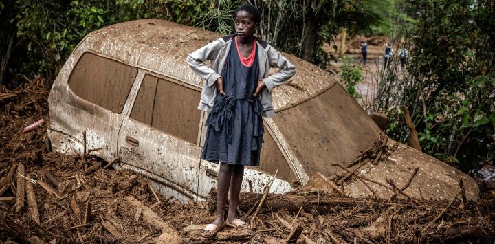 Una niña observa junto a un coche averiado enterrado en barro en una zona muy afectada por lluvias torrenciales e inundaciones repentinas en la aldea de Kamuchiri, cerca de Mai Mahiu, Kenia.