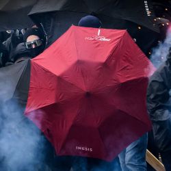 Los manifestantes se protegen detrás de paraguas abiertos mientras envían fuegos artificiales hacia la policía antidisturbios francesa durante una manifestación, que conmemora el Día Internacional de los Trabajadores, en Nantes, oeste de Francia. | Foto:LOIC VENANCE / AFP