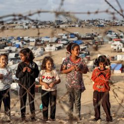 Niños se encuentran detrás de un alambre de púas a lo largo de una pendiente cerca de un campamento que alberga a palestinos desplazados en Rafah, en el sur de la Franja de Gaza, en medio del conflicto en curso en el territorio palestino entre Israel y el grupo militante Hamas. | Foto:AFP