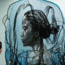 Un visitante observa la obra de arte del artista indonesio Iwan Yusuf titulada "Infinity" hecha con redes de pesca nuevas y usadas durante la feria de arte Jakarta Art Gardens en Yakarta. | Foto:Yasuyoshi Chiba / AFP