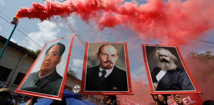 La gente muestra retratos de Mao Zedong, Lening y Marx durante una manifestación en Medellín, departamento de Antioquia, Colombia.