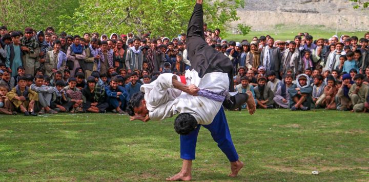 Los afganos se reúnen para ver competir a los luchadores tradicionales en un campo en el distrito de Baharak de la provincia de Badakhshan.