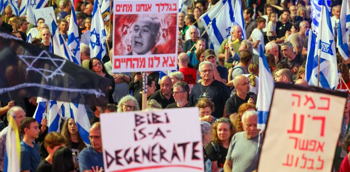 Los manifestantes sostienen pancartas y ondean banderas nacionales durante una manifestación antigubernamental en la ciudad costera israelí de Tel Aviv, en medio del conflicto en curso entre Israel y el grupo militante Hamas.