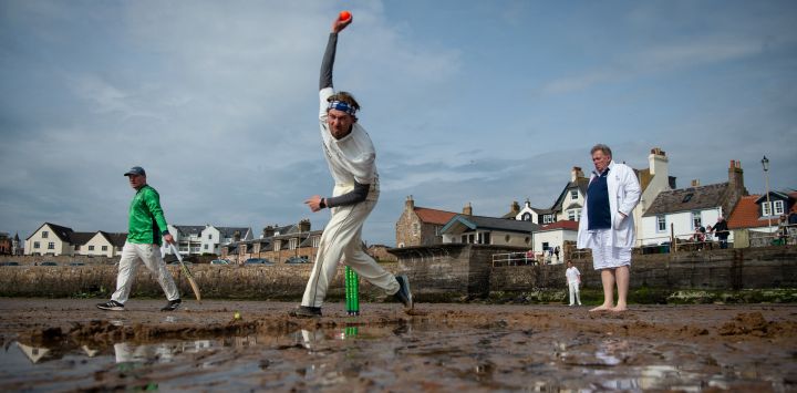 Los jugadores de Ship Inn CC y The South Street Swingers CC, un equipo formado por ex miembros del equipo de la Universidad de Edimburgo, juegan un partido de cricket en la playa de Elie, en la costa sur de Fife, en el este de Escocia.