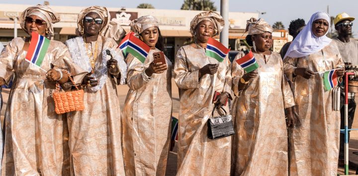Sus partidarios ondean banderas de Gambia al costado de la carretera mientras el presidente de Gambia, Adama Barrow, llega al Centro Internacional de Conferencias Sir Dawda Kairaba Jawara durante la Cumbre 2024 de la Organización de Cooperación Islámica (OCI) en Banjul.