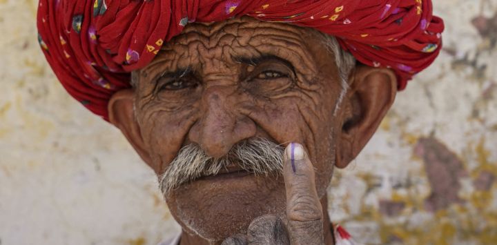Un hombre muestra su dedo entintado después de emitir su voto en un colegio electoral durante la segunda fase de la votación en las elecciones generales de la India, en Ajmer.