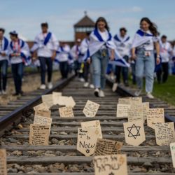 Placas de madera con mensajes y oraciones colocadas por los participantes en una vía férrea que conduce al antiguo campo de exterminio nazi de Auschwitz-Birkenau en Brzezinka, cerca de Auschwitz, Polonia, aparecen fotografiadas durante la Marcha para honrar a las víctimas del Holocausto en el Memorial y Museo Auschwitz II-Birkenau. | Foto:Wojtek Radwanski / AFP